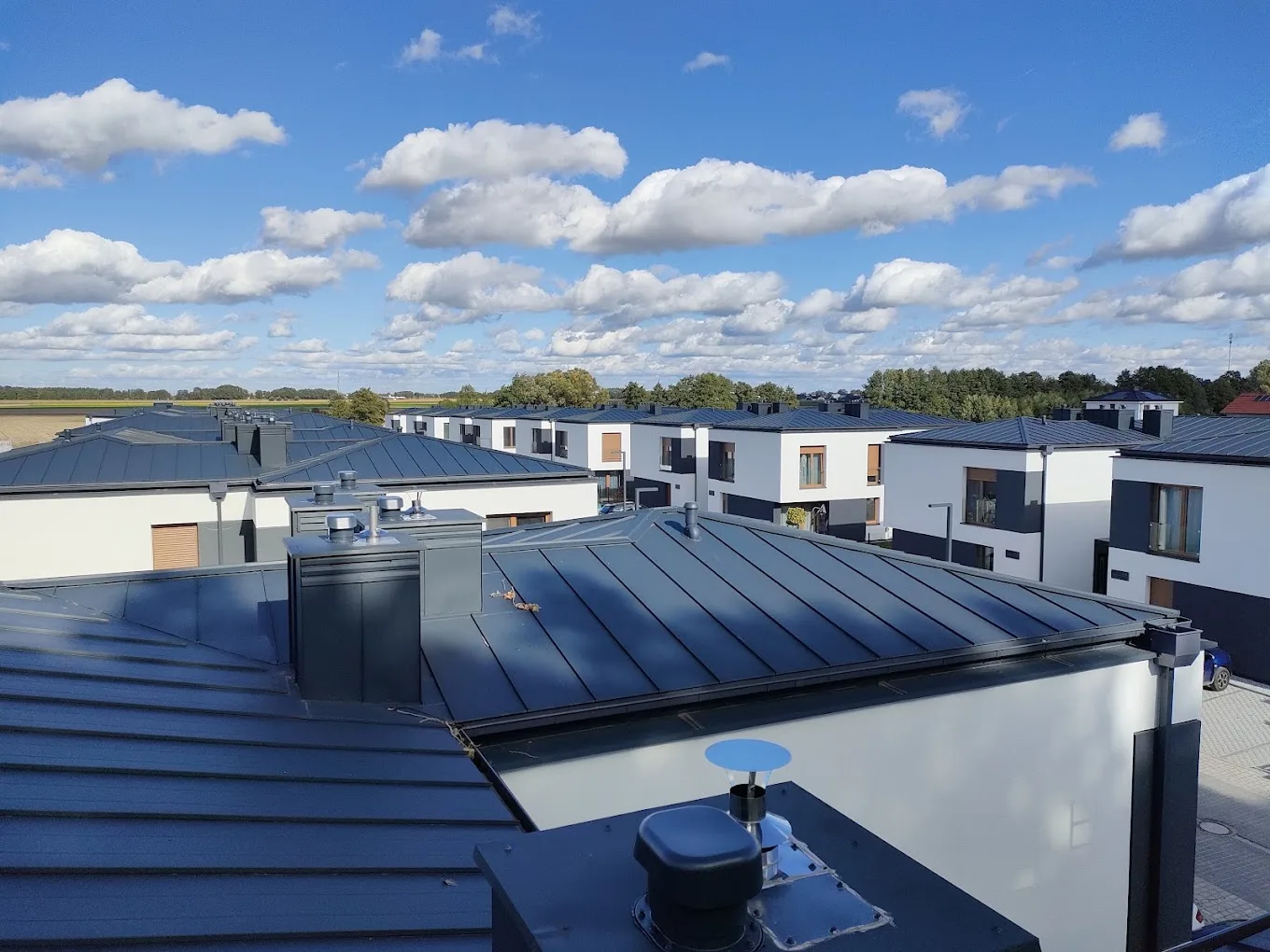 Panorama dachów osiedla domów jednorodzinnych krytych blachą na rąbek stojący, realizacja Mich-Bud